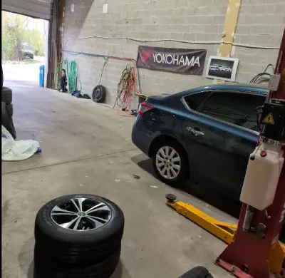 A car in our service bay with a set of tires waiting beside it
